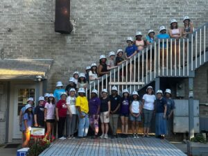 A group of volunteers in hard hats line a staircase